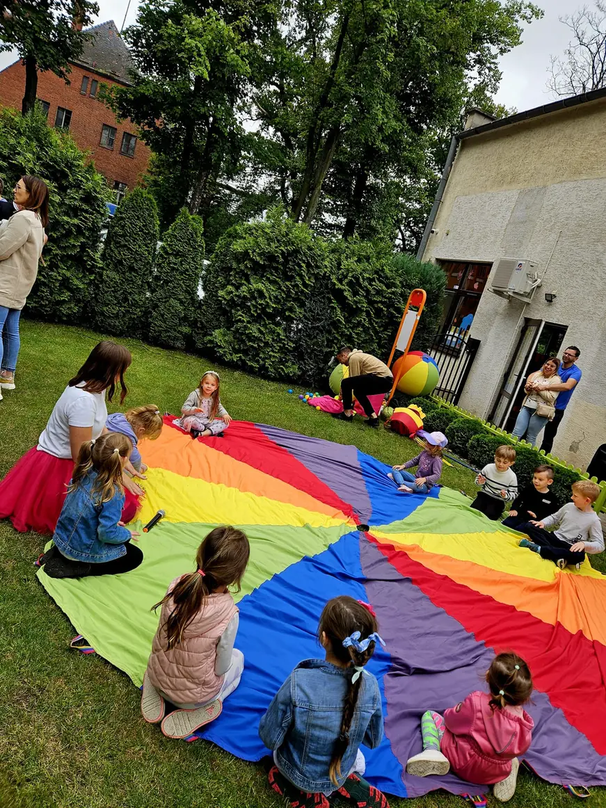 Dzieci i animatorka bawią się dużą kolorową chustą